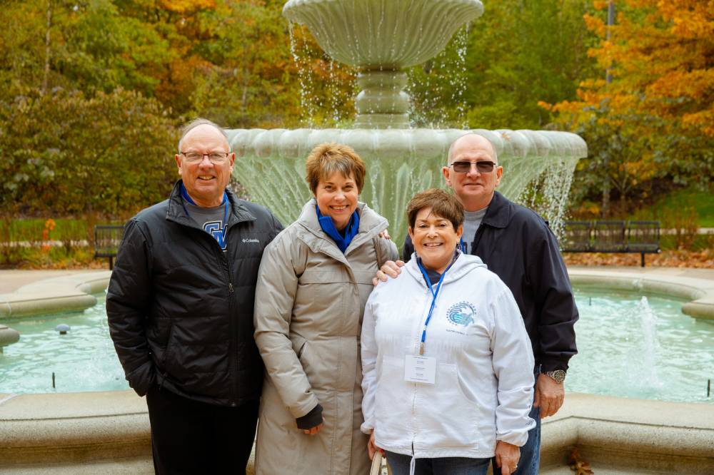 four people smiling by the fountain